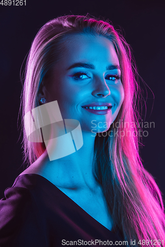 Image of Caucasian woman\'s portrait isolated on dark studio background in neon light