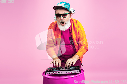 Image of Senior hipster man wearing eyeglasses posing on pink background. Tech and joyful elderly lifestyle concept