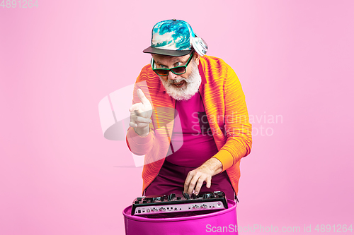 Image of Senior hipster man wearing eyeglasses posing on pink background. Tech and joyful elderly lifestyle concept