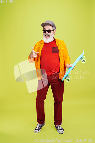 Image of Senior hipster man wearing eyeglasses posing on green background. Tech and joyful elderly lifestyle concept