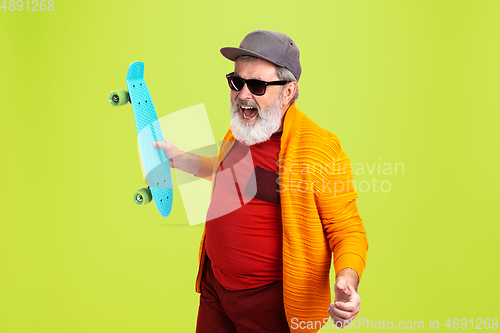 Image of Senior hipster man wearing eyeglasses posing on green background. Tech and joyful elderly lifestyle concept