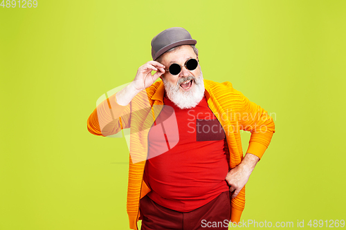 Image of Senior hipster man wearing eyeglasses posing on green background. Tech and joyful elderly lifestyle concept