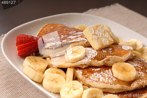 Image of Banana pancakes with maple syrup and a strawberrry