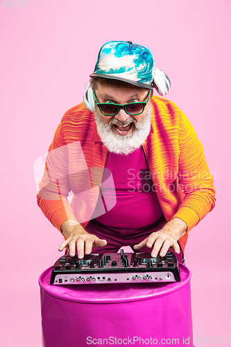 Image of Senior hipster man wearing eyeglasses posing on pink background. Tech and joyful elderly lifestyle concept