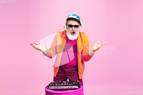 Image of Senior hipster man wearing eyeglasses posing on pink background. Tech and joyful elderly lifestyle concept