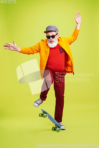 Image of Senior hipster man wearing eyeglasses posing on green background. Tech and joyful elderly lifestyle concept