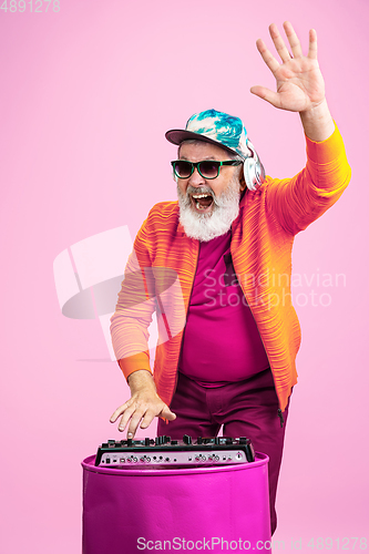 Image of Senior hipster man wearing eyeglasses posing on pink background. Tech and joyful elderly lifestyle concept