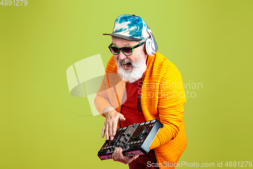 Image of Senior hipster man wearing eyeglasses posing on green background. Tech and joyful elderly lifestyle concept