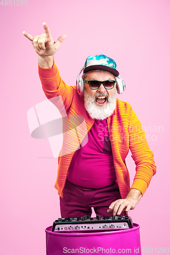 Image of Senior hipster man wearing eyeglasses posing on pink background. Tech and joyful elderly lifestyle concept