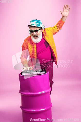 Image of Senior hipster man wearing eyeglasses posing on pink background. Tech and joyful elderly lifestyle concept