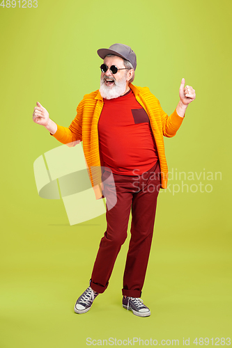 Image of Senior hipster man wearing eyeglasses posing on green background. Tech and joyful elderly lifestyle concept