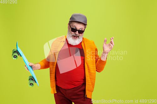 Image of Senior hipster man wearing eyeglasses posing on green background. Tech and joyful elderly lifestyle concept