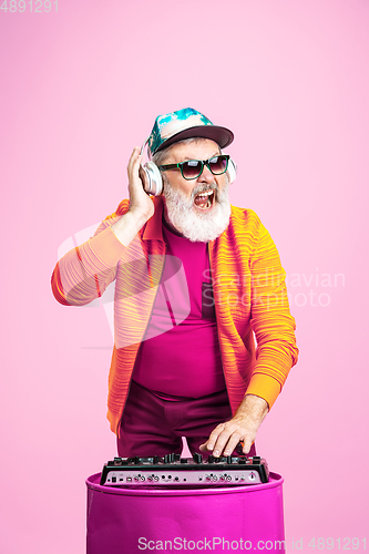 Image of Senior hipster man wearing eyeglasses posing on pink background. Tech and joyful elderly lifestyle concept