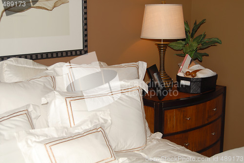 Image of Bed with white bedspread and nightstand in the corner