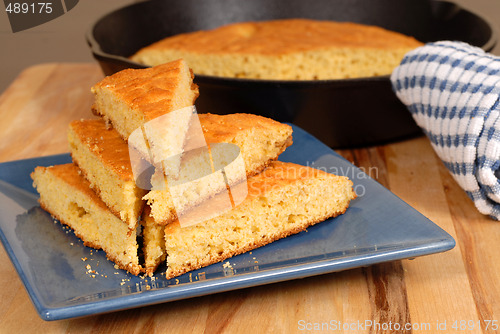 Image of Stack of cornbread on a blue plate with skillet in background