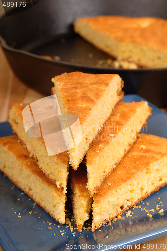 Image of Stack of cornbread on blue plate with black skillet in backgroun