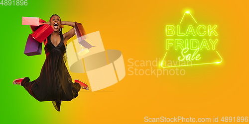 Image of Portrait of young woman in neon light on gradient backgound. The human emotions, black friday, cyber monday, purchases, sales, finance concept. Neoned lettering.