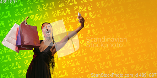 Image of Portrait of young woman in neon light on gradient backgound. The human emotions, black friday, cyber monday, purchases, sales, finance concept. Neoned lettering.