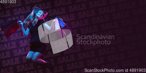 Image of Portrait of young woman in neon light on dark backgound. The human emotions, black friday, cyber monday, purchases, sales, finance concept. Neoned lettering.