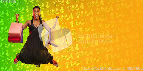 Image of Portrait of young woman in neon light on gradient backgound. The human emotions, black friday, cyber monday, purchases, sales, finance concept. Neoned lettering.