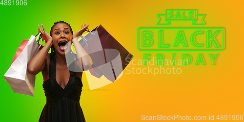 Image of Portrait of young woman in neon light on gradient backgound. The human emotions, black friday, cyber monday, purchases, sales, finance concept. Neoned lettering.