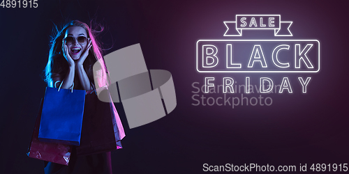 Image of Portrait of young woman in neon light on dark backgound. The human emotions, black friday, cyber monday, purchases, sales, finance concept. Neoned lettering.