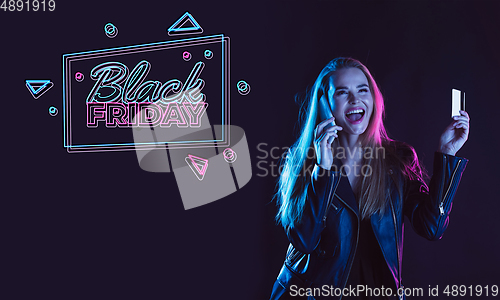 Image of Portrait of young woman in neon light on dark backgound. The human emotions, black friday, cyber monday, purchases, sales, finance concept. Neoned lettering.