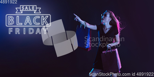 Image of Portrait of young woman in neon light on dark backgound. The human emotions, black friday, cyber monday, purchases, sales, finance concept. Neoned lettering.