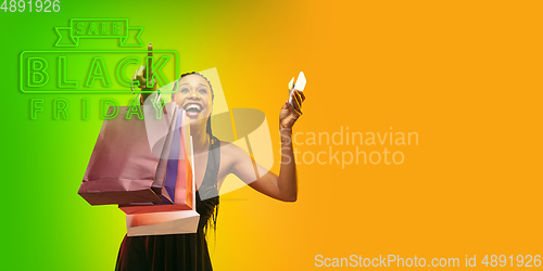 Image of Portrait of young woman in neon light on gradient backgound. The human emotions, black friday, cyber monday, purchases, sales, finance concept. Neoned lettering.