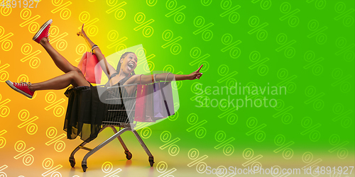 Image of Portrait of young woman in neon light on gradient backgound. The human emotions, black friday, cyber monday, purchases, sales, finance concept. Neoned lettering.