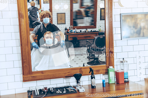 Image of Man getting hair cut at the barbershop wearing mask during coron