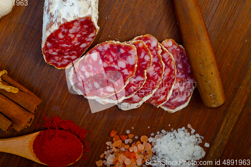 Image of traditional Italian salame cured sausage sliced on a wood board