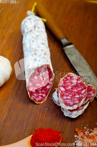 Image of traditional Italian salame cured sausage sliced on a wood board