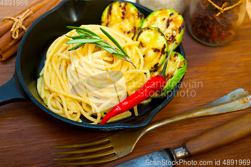 Image of italian spaghetti pasta with zucchini sauce on iron skillet