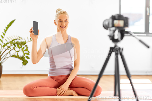 Image of woman with phone streaming for yoga blog at home