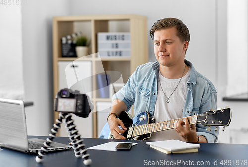 Image of man or blogger with camera playing guitar at home