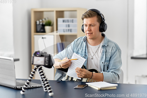 Image of man or blogger with camera, music book and guitar