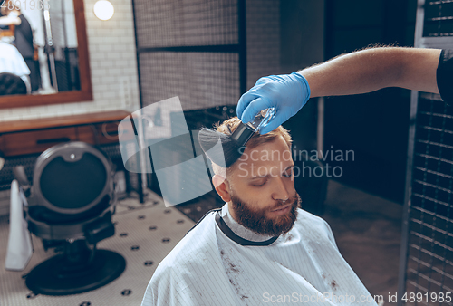 Image of Man getting hair cut at the barbershop wearing mask during coronavirus pandemic