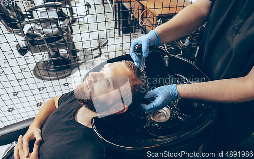 Image of Man getting hair cut at the barbershop wearing mask during coronavirus pandemic