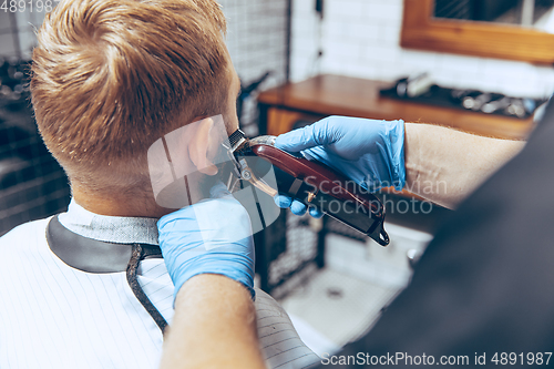 Image of Man getting hair cut at the barbershop wearing mask during coronavirus pandemic