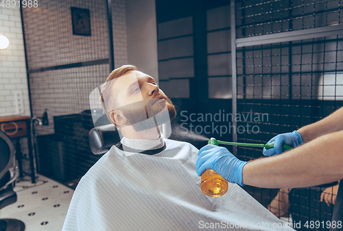 Image of Man getting hair cut at the barbershop wearing mask during coronavirus pandemic