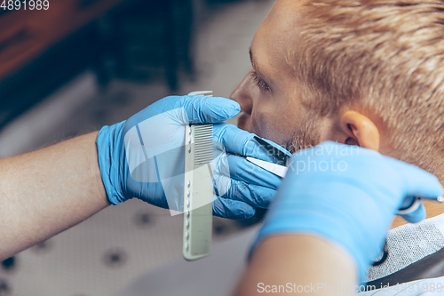 Image of Man getting hair cut at the barbershop wearing mask during coronavirus pandemic