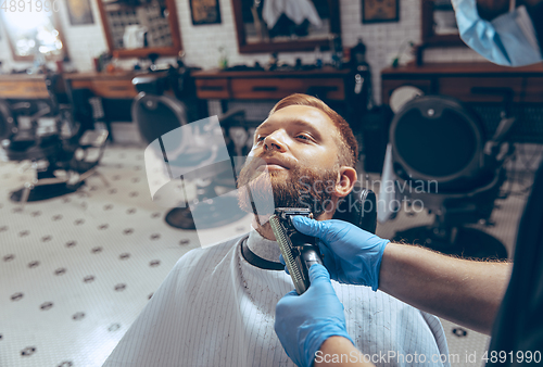 Image of Man getting hair cut at the barbershop wearing mask during coronavirus pandemic