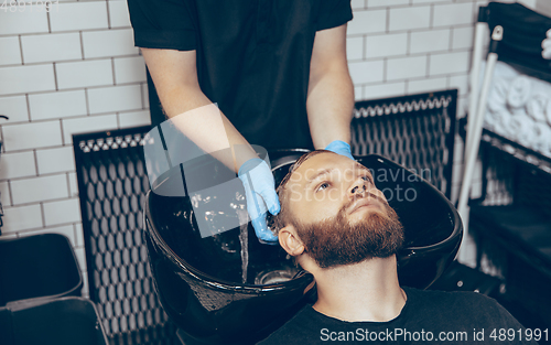 Image of Man getting hair cut at the barbershop wearing mask during coronavirus pandemic