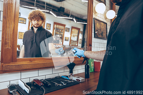 Image of Male barber at the barbershop wearing gloves preparing working p