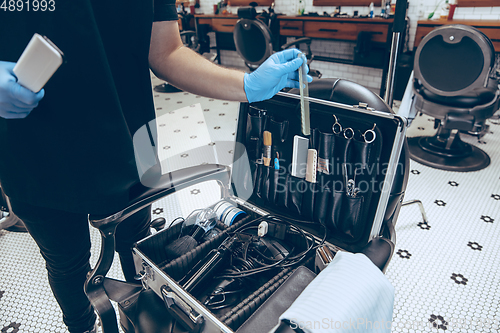 Image of Male barber at the barbershop wearing gloves preparing working place for client