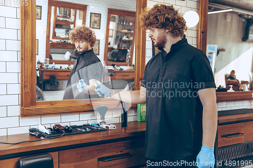 Image of Male barber at the barbershop wearing gloves preparing working p