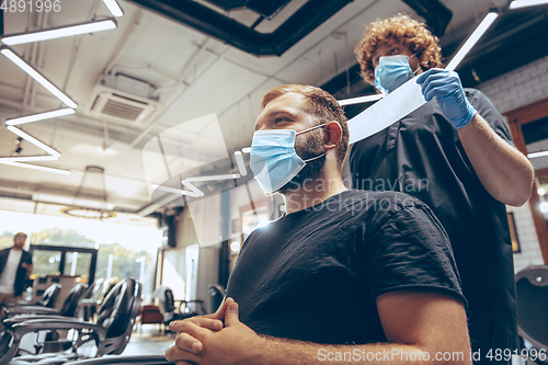 Image of Man getting hair cut at the barbershop wearing mask during coron