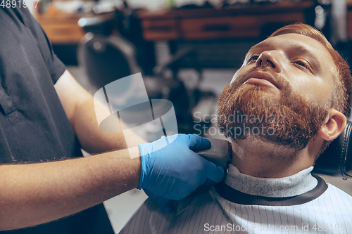 Image of Man getting hair cut at the barbershop wearing mask during coronavirus pandemic