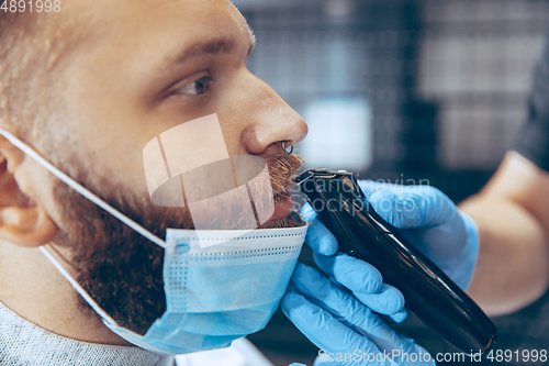 Image of Man getting hair cut at the barbershop wearing mask during coronavirus pandemic